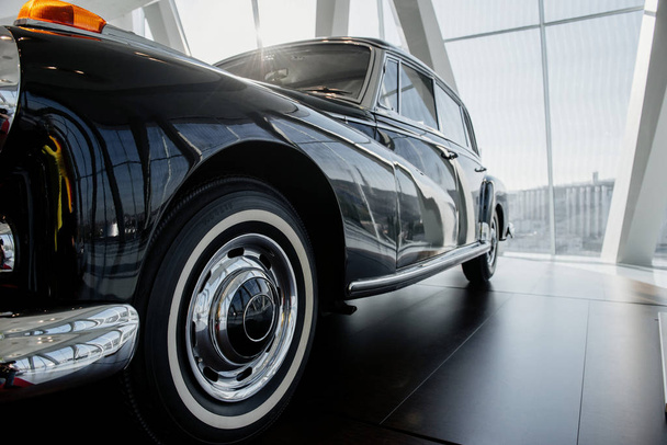 Shiny look. Ground view. Front left side of rare car standing on black tile indoors. - Photo, Image