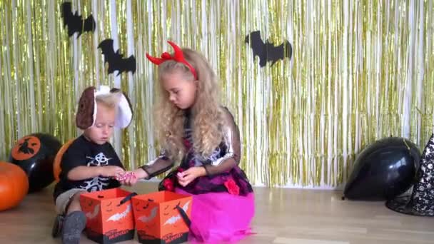Adorables niños mejores amigos compartiendo y comiendo dulces en la fiesta de Halloween
 - Metraje, vídeo