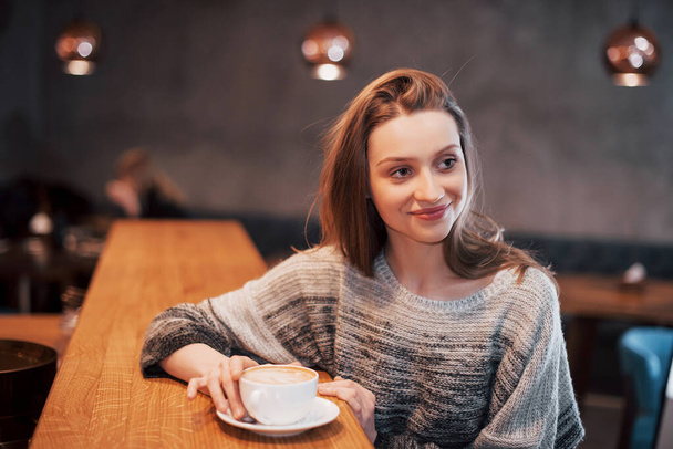 pretty young woman sitting in the cafe with a cup of tea. - 写真・画像