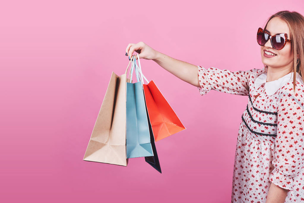 Portrait of young happy smiling woman with shopping bags on the pink Background. - Foto, imagen