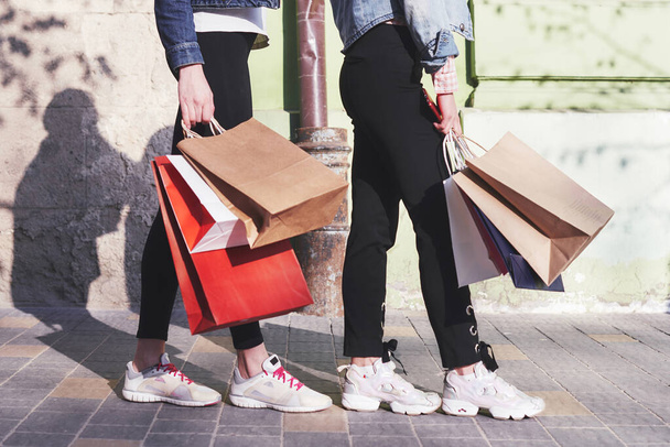 Two young woman carrying shopping bags while walking in the street after visiting the stores. - Foto, afbeelding