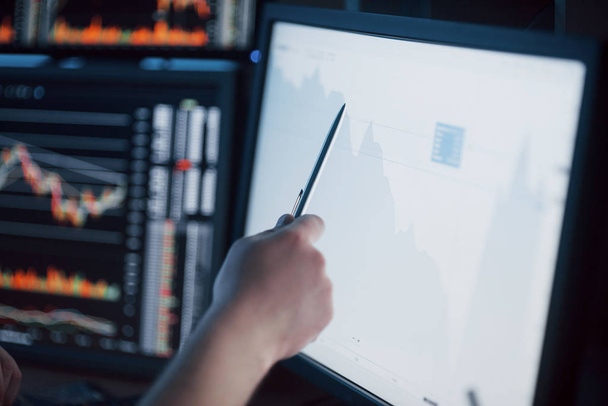 Analyzing data. Close-up of young businessman pointing on the data presented in the chart with pen while working in creative office. - Φωτογραφία, εικόνα