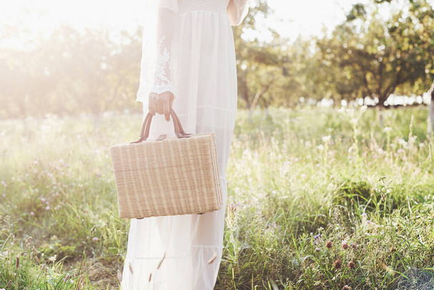 Beautiful young woman wearing elegant white dress and enjoying beautiful sunny afternoon in a summer garden. - Foto, immagini