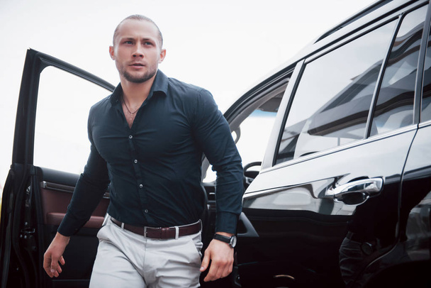 Portrait of a young bodyguard near the car. He performs dangerous work. - 写真・画像