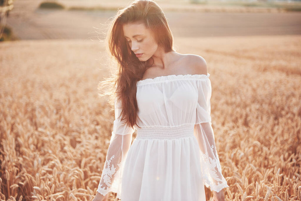 Happy young girl in a wheat field under sunlight - Photo, Image