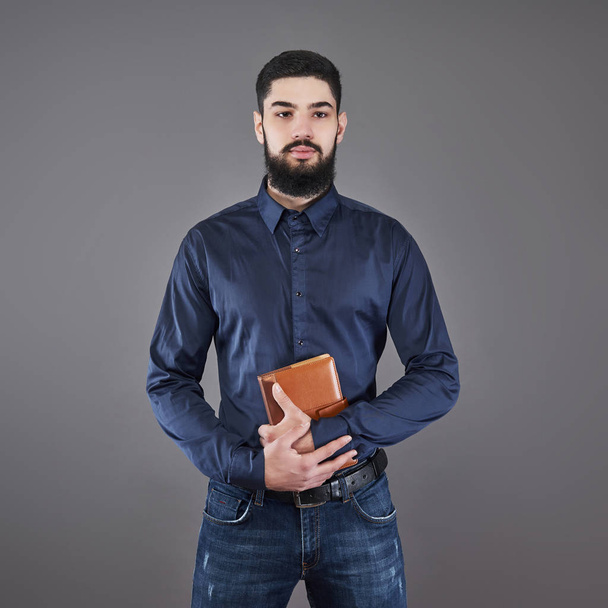 Portrait of toothy handsome bearded man with book on hands. - 写真・画像