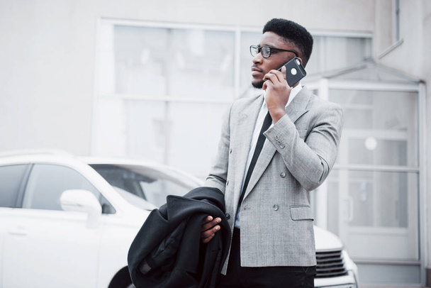 Portrait of a confident young businessman walking in the city talking on cell phone. - Photo, Image