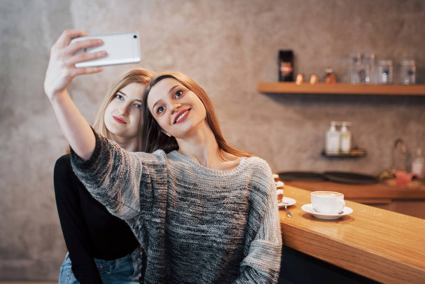 Two women friends sitting in cafe and make selfie. - Foto, Imagen
