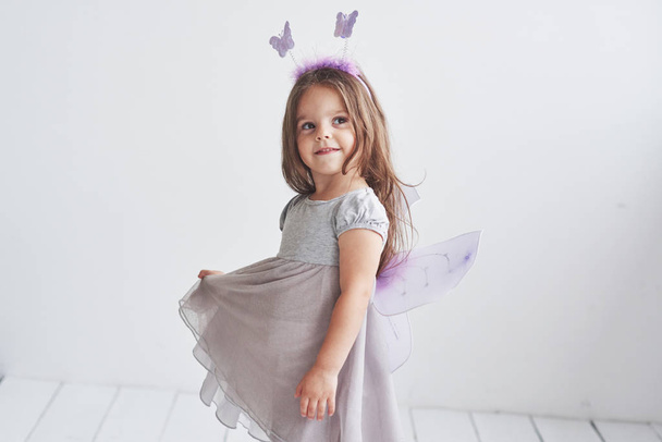Dreamy look. Imagination is powerful thing. Lovely little girl in the fairy costume standing in room with white background. - Foto, Imagem