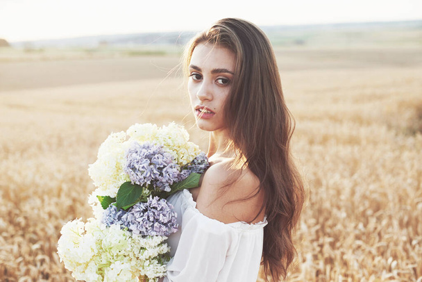 Beautiful girl in white dress running on the autumn field of wheat at sunset time. - Foto, immagini