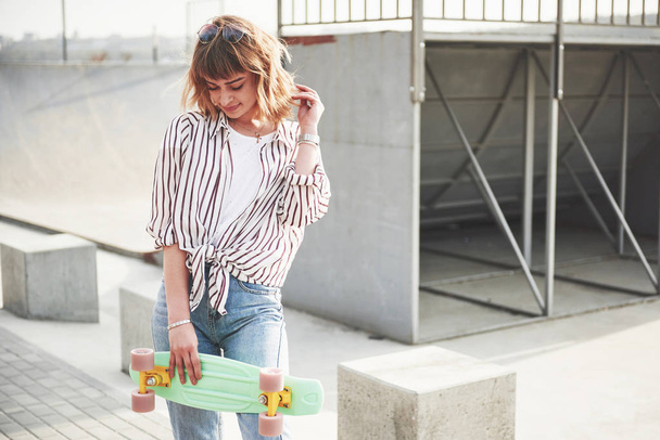 Stylish beautiful young woman with a skateboard, on a beautiful summer sunny day - Φωτογραφία, εικόνα