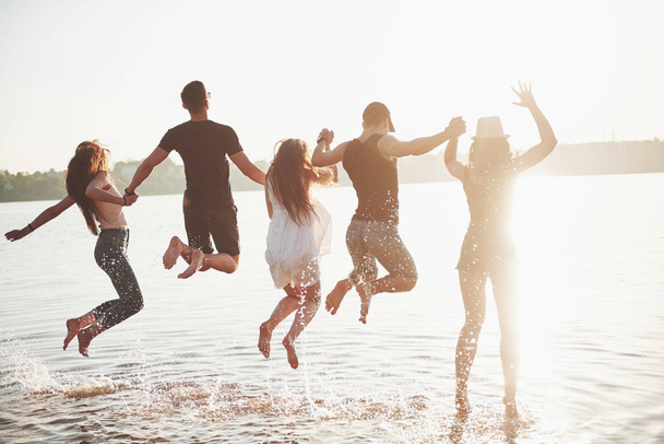 Gelukkige vrienden hebben plezier op het strand - Jongeren spelen in open lucht op zomervakantie. - Foto, afbeelding
