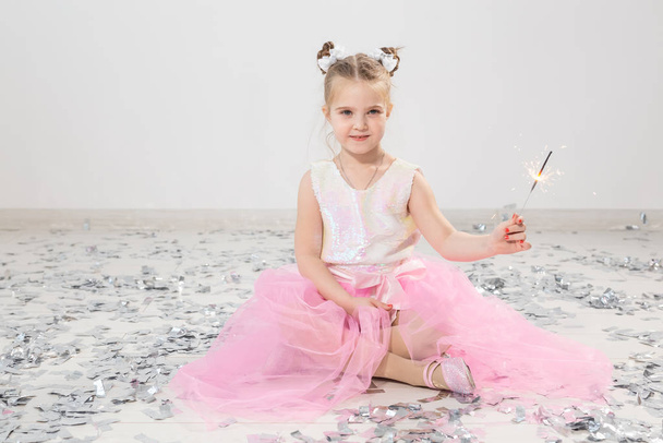 Holidays, christmas, birthday party and new year concept - child holding burning sparkler. After funny party. - Photo, Image