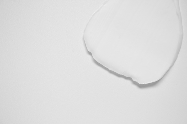 Smear moisturizing cream on white background with copy space, top view. Creamy texture of beauty product horizontal photo - Fotó, kép