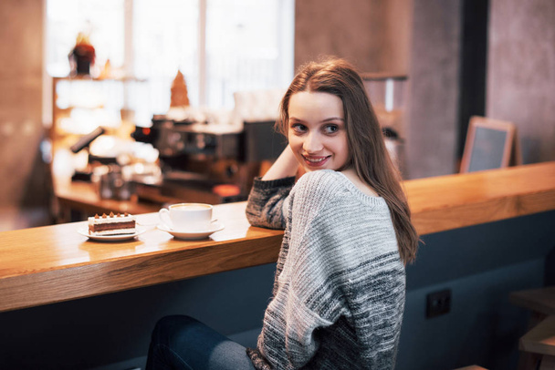 Happy smiling young woman using phone in a cafe. Beautiful girl in trendy spring colors. - 写真・画像