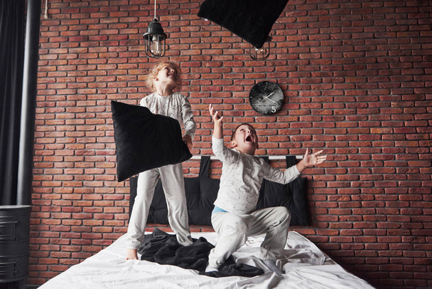 Crianças impertinentes menino e menina encenou uma luta travesseiro na cama no quarto. Eles gostam desse tipo de jogo.. - Foto, Imagem