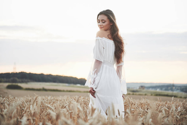 Portrait of a beautiful girl in a white dress in the field of wheat. - Фото, изображение