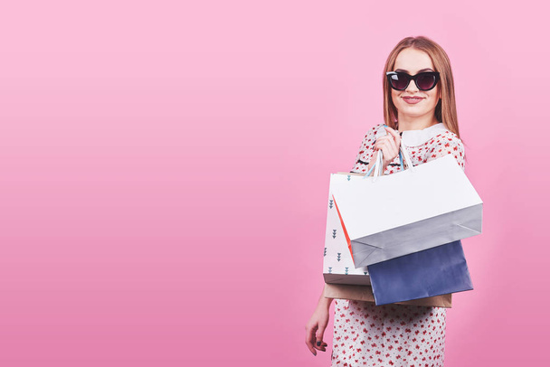 Portrait of young happy smiling woman with shopping bags on the pink Background. - Φωτογραφία, εικόνα