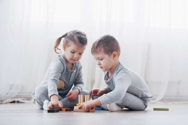 Children play with a toy designer on the floor of the children's room. Two kids playing with colorful blocks. Kindergarten educational games. - Photo, Image