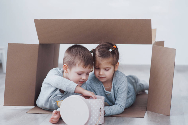 Two a little kids boy and girl playing in cardboard boxes. Concept photo. Children have fun. - Foto, Imagem