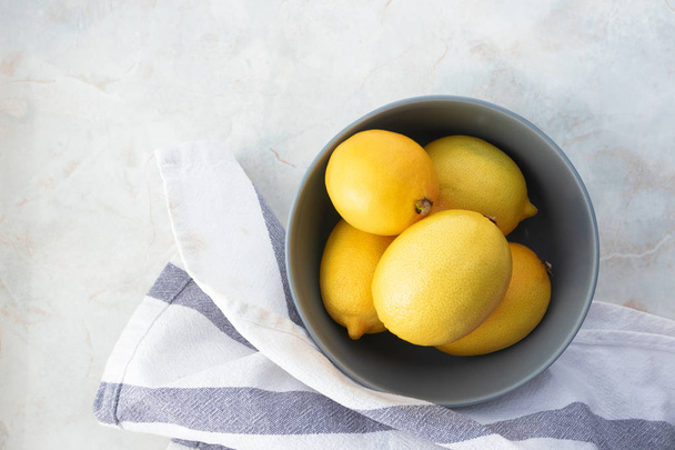 Raw fresh yellow lemon in bowl and towel on marble table, top vi - Фото, зображення