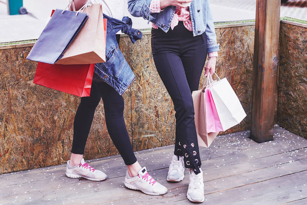 Две молодые женщины несли сумки с покупками, когда шли по улице после посещения магазинов
. - Фото, изображение