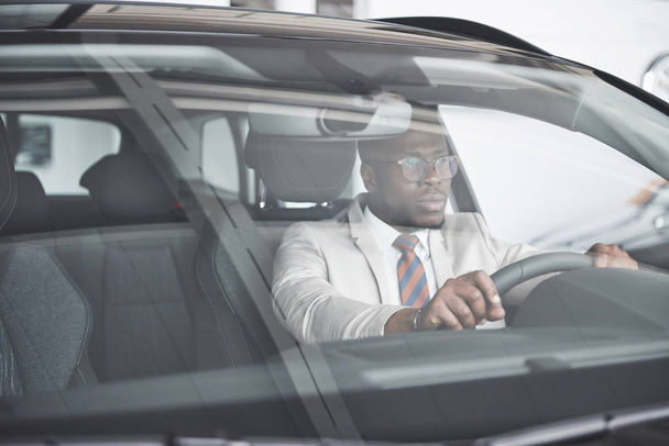 Frontansicht schöner afrikanischer eleganter Geschäftsmann fährt Auto. - Foto, Bild