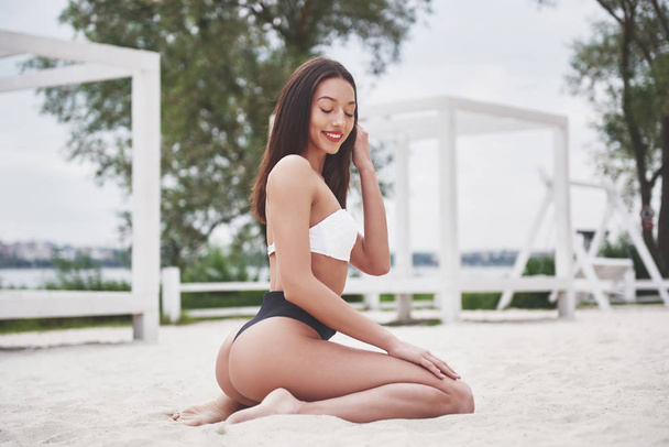 Beautiful slim luxury girl in bikini on the sand beach on a tropical island. Sexy tanned body and perfect figure. - Φωτογραφία, εικόνα