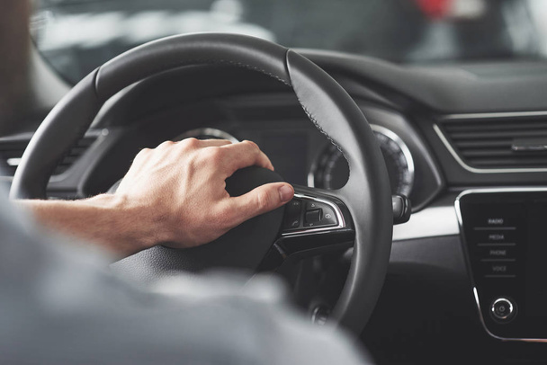 Man's big hands on a steering wheel while driving a car - Fotó, kép