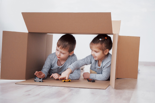 Baby brother and child sister playing in cardboard boxes in nursery. - Φωτογραφία, εικόνα