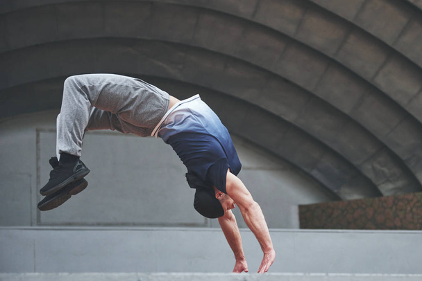 The man outdoors practices parkour, extreme acrobatics - Foto, Imagen