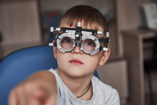 Shows an index finger. Close up portrait of child in special glasses. - Foto, Imagen