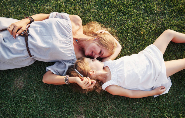 felice bambina e sua madre si divertono all'aperto sull'erba verde nella soleggiata giornata estiva
. - Foto, immagini