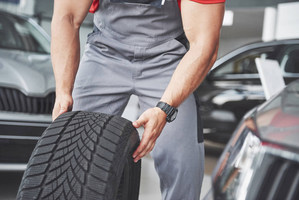 Mechanic holding a tire tire at the repair garage. replacement of winter and summer tires. - 写真・画像