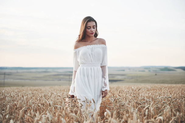 Happy young girl in a wheat field under sunlight - Fotoğraf, Görsel