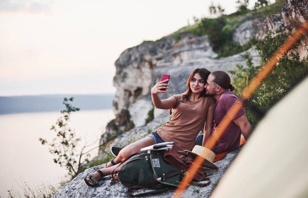 Let's take selfie. Two person sitting on the rock and watching gorgeous nature - Foto, Imagem