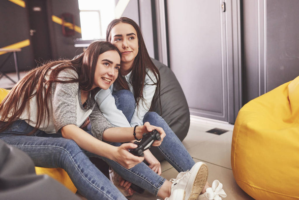 Twin sister sisters play on the console. Girls hold joysticks in their hands and have fun. - Fotoğraf, Görsel