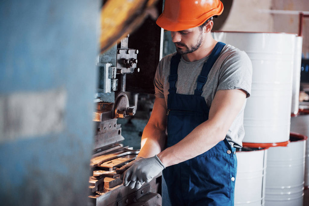 Porträt eines jungen Arbeiters mit hartem Hut in einer großen Recyclingfabrik. Der Ingenieur überwacht die Arbeit von Maschinen und anderen Geräten. - Foto, Bild