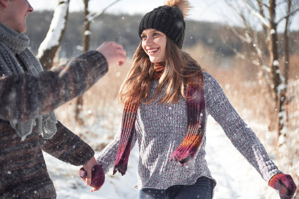 Couple has fun and laughs. kiss. Young hipster couple hugging each other in winter park. Winter love story, a beautiful stylish young couple. Winter fashion concept with boyfriend and girlfriend. It is snowing - Foto, imagen