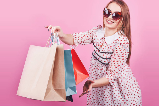 Portrait of young happy smiling woman with shopping bags on the pink Background. - Photo, image