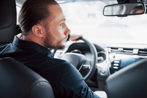 Rear view of confident young businessman sitting at the wheel of his new car. - Fotoğraf, Görsel