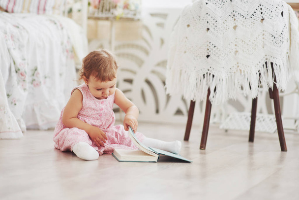 Beautiful little girl read book with her favorite bear on a soft plush blanket. - 写真・画像