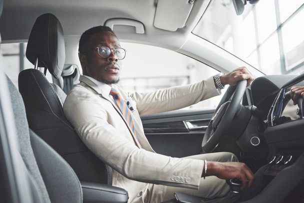Stylish black businessman sitting behind the wheel of new luxury car. Rich african american man. - Foto, Bild