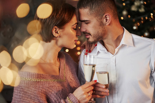 Desire is in the air. Nice couple celebrating new year indoors with classic beautiful clothes on they. - Fotó, kép