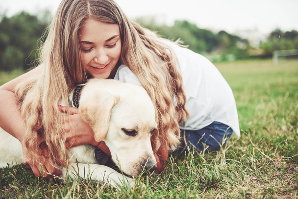 Frame with a beautiful girl with a beautiful dog in a park on green grass - Foto, imagen