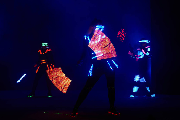 Laser show performance, dancers in led suits with LED lamp, very beautiful night club performance, party. - Fotó, kép