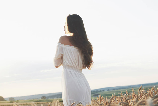 Beautiful girl in white dress running on the autumn field of wheat at sunset time. - Fotoğraf, Görsel