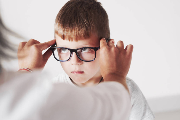 Funny kid. Doctor giving the child new black glasses for his vision. - Zdjęcie, obraz