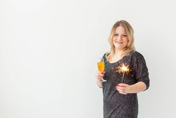 Vacances, Noël, anniversaire et concept de nouvelle année - Femme célébrer et tient le vin dans un verre et mousseux sur fond blanc, gros plan
 - Photo, image