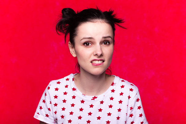 όμορφη συναισθηματική κοπέλα σε ένα t-shirt σε ένα κόκκινο φόντο - Φωτογραφία, εικόνα
